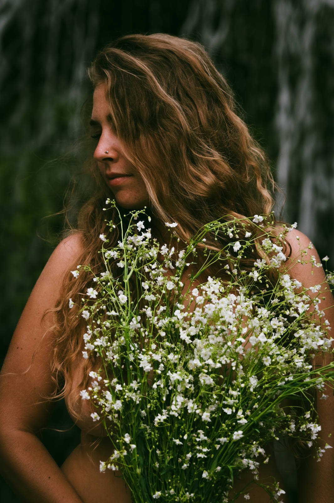 A woman with long hair holding a large bouquet of white flowers.