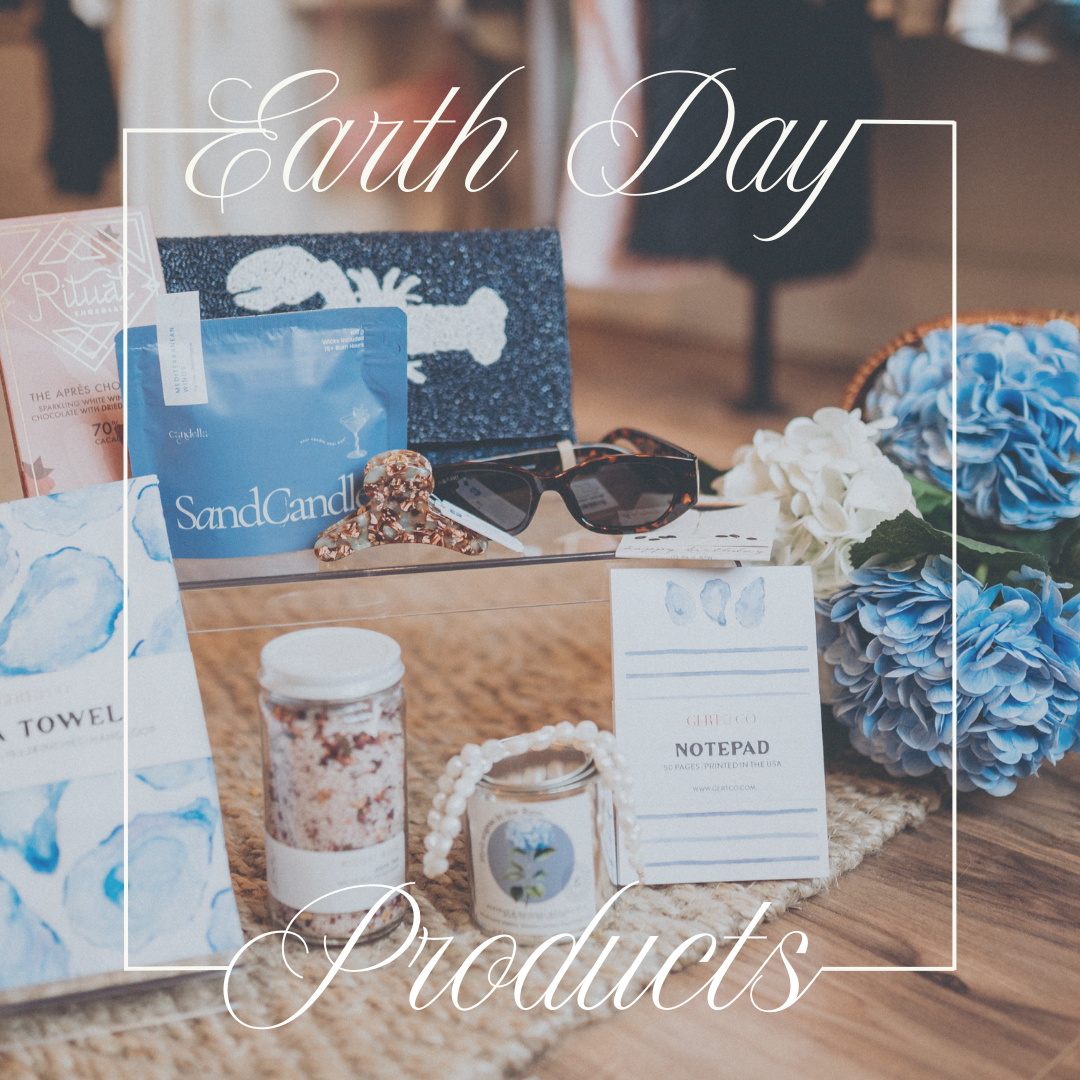 Display of Earth Day products including candles, notebooks, flowers, sunglasses, and skincare items on a wooden table.