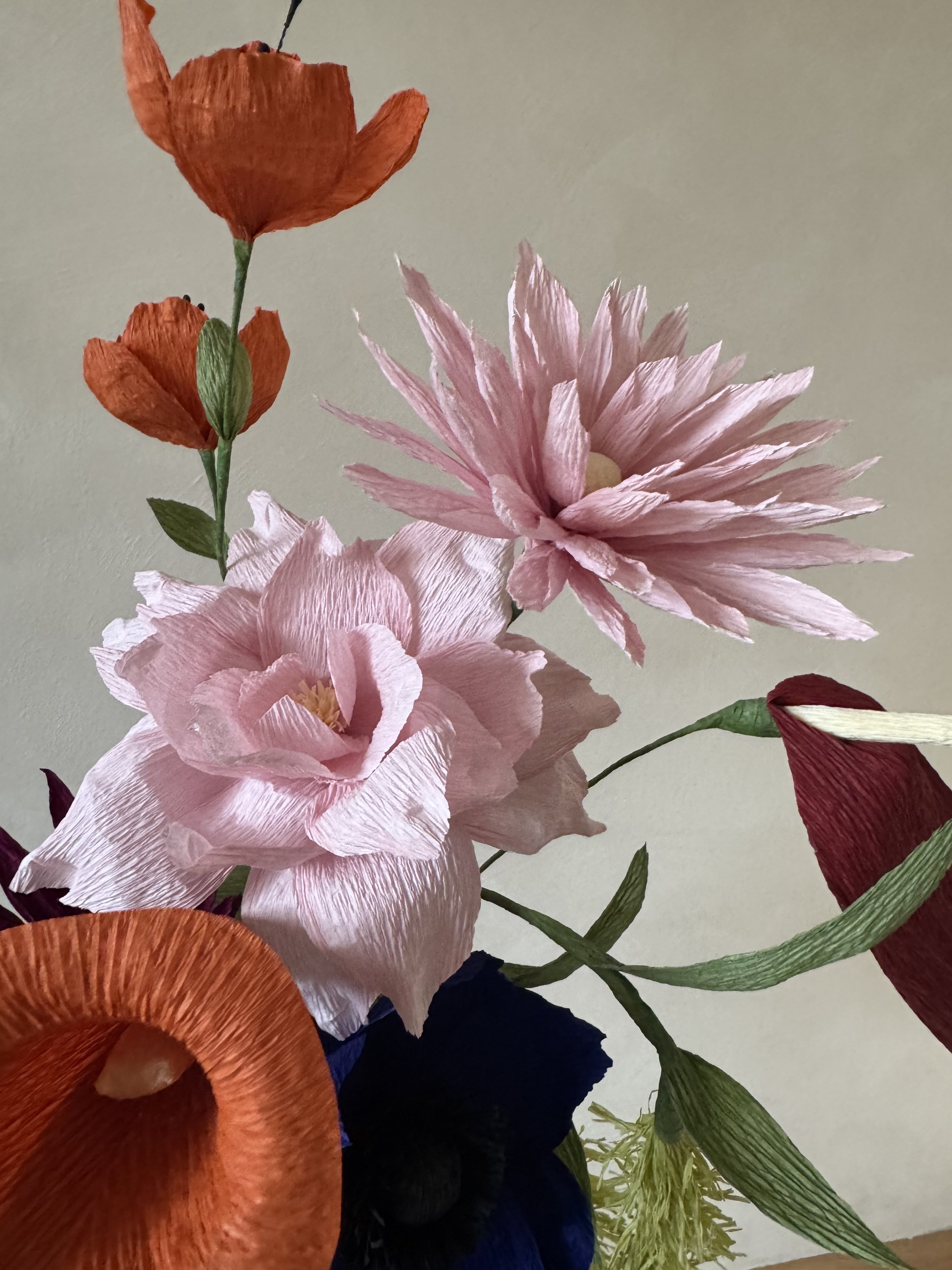 Ein Strauß mit 7 oder 10 handgefertigten Blüten aus feinem Krepppapier – darunter Anthurie, Amaranthus, Anemone, Rose, Dahlie, Calla und Rittersporn. Ihr könnt zwischen 2 Größen wählen.