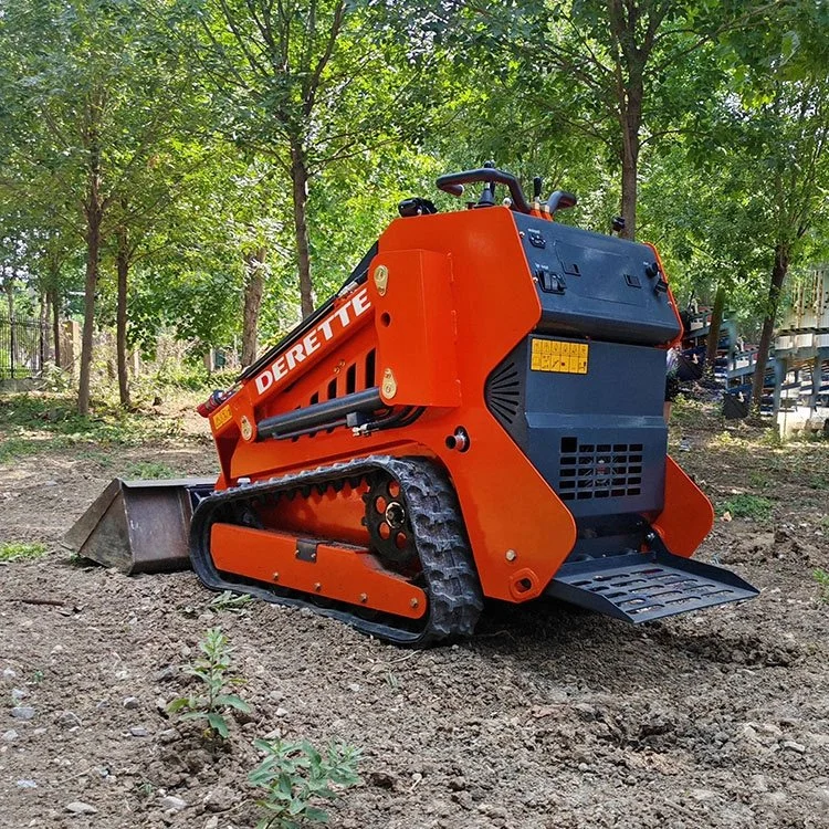 Orange mini skid steer loader on dirt in a forested area