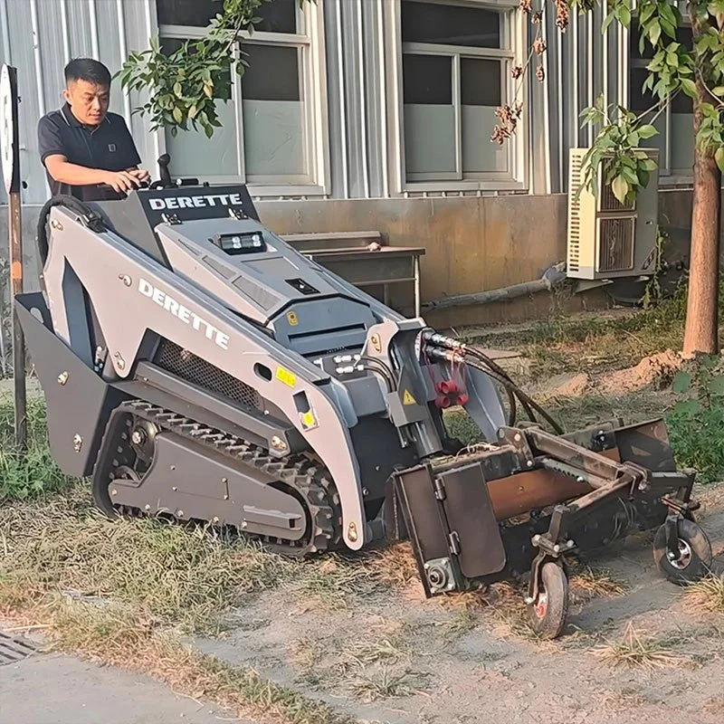 Small earth-moving machine labeled "DERETTE" with operator, near building.