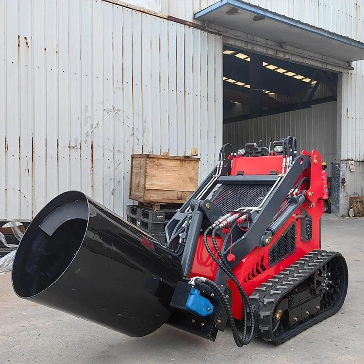 Red tracked mini skid steer loader with black hydraulic attachment in front of warehouse.