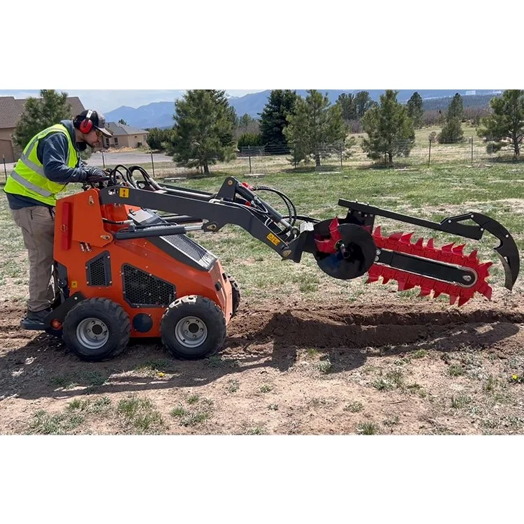 Person operating an orange mini skid steer loader with attachments on a grassy field, wearing safety gear.