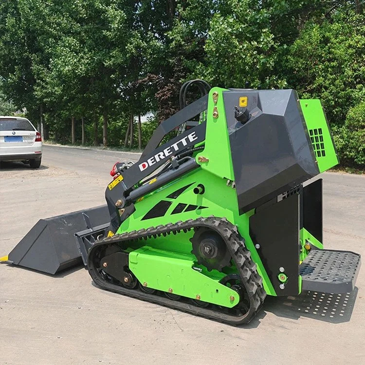 Green mini skid steer loader with tracks and "Derette" branding on a paved surface with trees in the background.