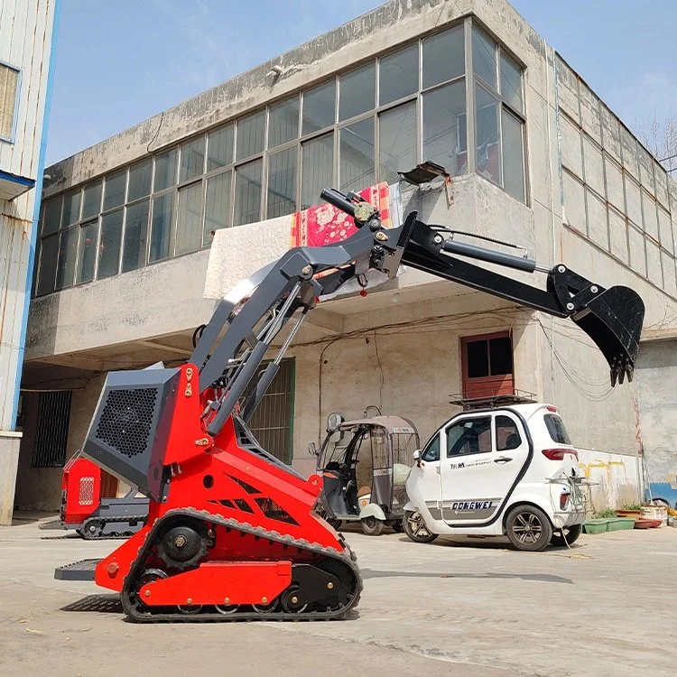 Mini excavator with red and black colors parked outside a building near a small white vehicle.