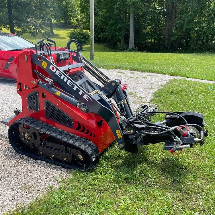 Red mini skid steer loader on gravel and grass