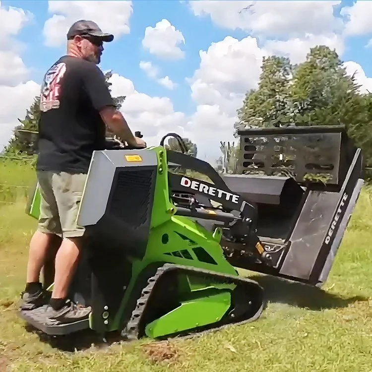 Man operating a compact green track loader with "Derette" branding on a grassy field.