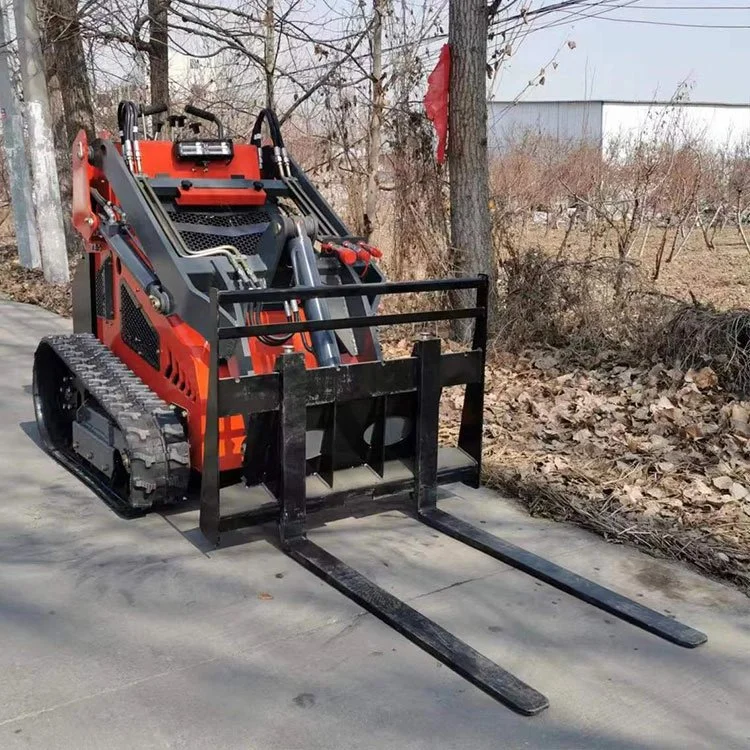 Compact orange skid steer loader with forklift attachment on a rural road.