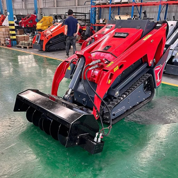 Red mini skid steer loader in warehouse with attachments