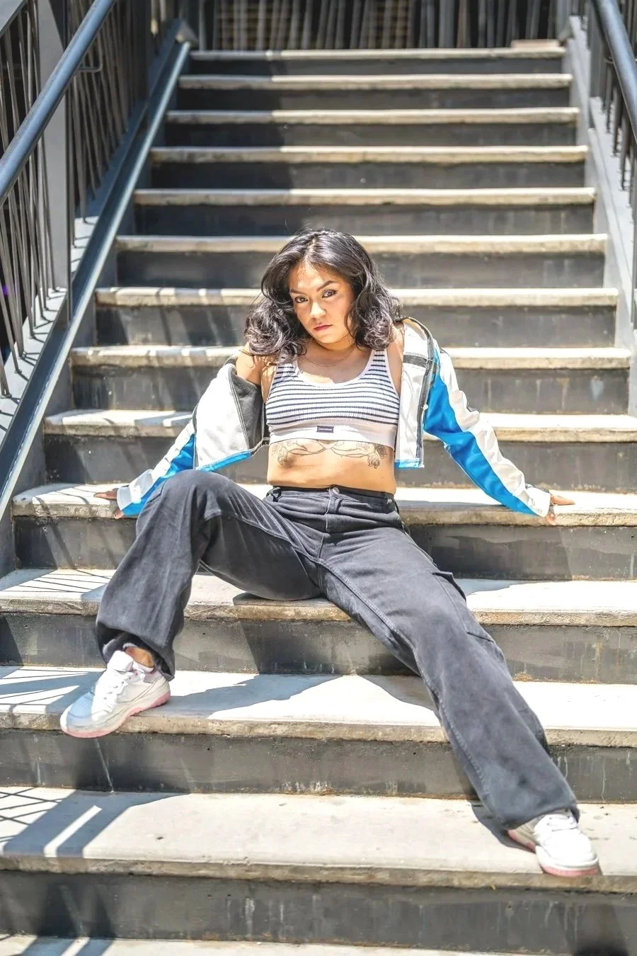 woman with black hair possing on a set of stairs