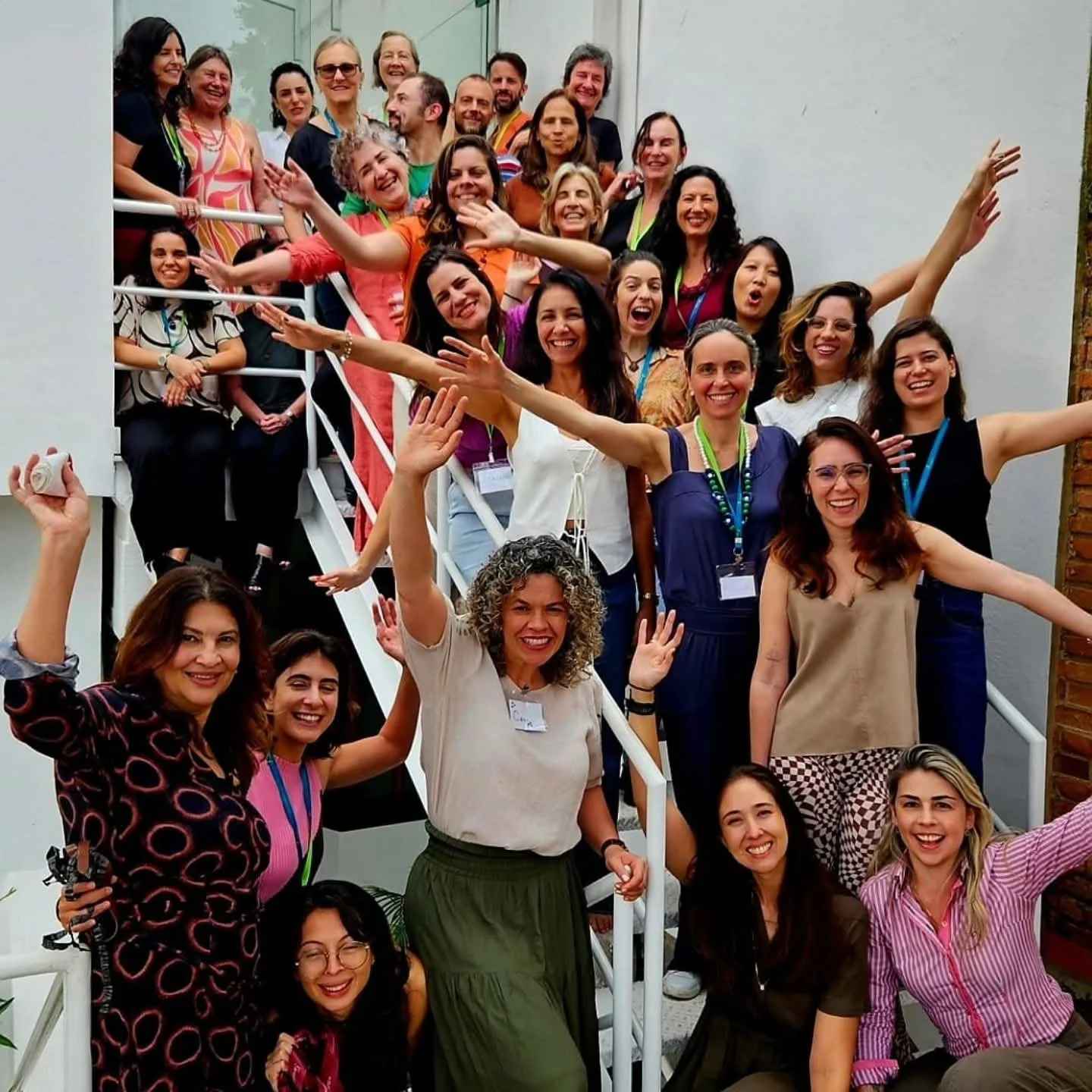 Grupo de mulheres sorridentes e felizes posando em escada ao ar livre, celebrando um evento ou encontro.