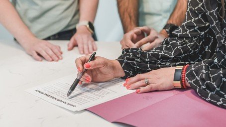 People reviewing and signing a real estate offer document, representing a sale-contingent offer.
