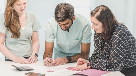 Buyers and real estate agent signing purchase documents during a Texas home buying transaction.