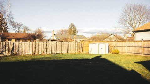 Residential backyard with wooden fence, shed, and lawn representing property-line changes.