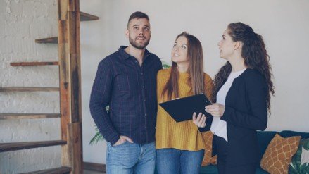 Young couple touring a home with a real estate agent while discussing first-time buyer options.