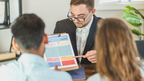 Real estate professional reviewing a home inspection checklist with sellers at a table.