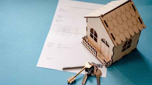 Miniature house, keys, and real estate contract paperwork representing a home appraisal gap.