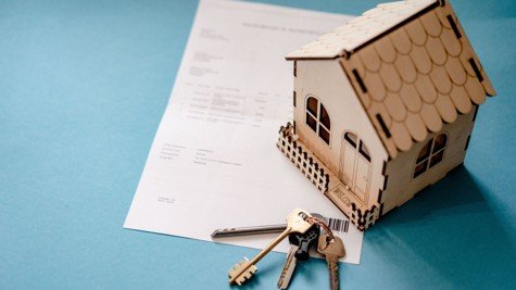 House keys, miniature home, and contract paperwork representing option fee and earnest money in Texas real estate.