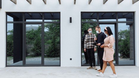 Real estate agent showing buyers a modern home exterior during a home tour.