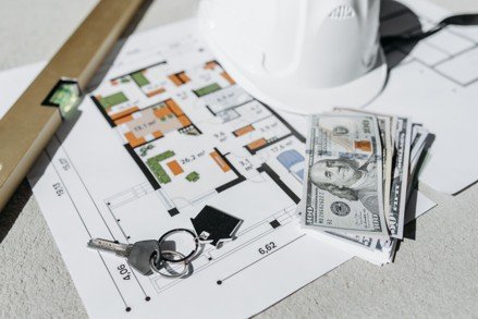 House keys, cash, and a floor plan representing down payment assistance and home buying costs.