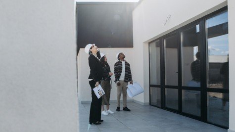 Real estate professionals and buyers reviewing a home exterior and roof during a property assessment.
