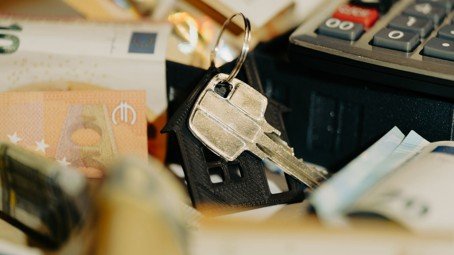 House keys, money, and a calculator representing bridge loan and HELOC financing for a move-up home purchase.