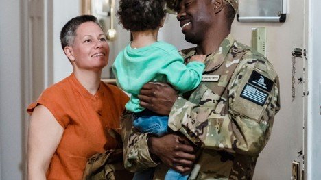 Military family standing in a home, representing VA loan benefits for Mansfield home buyers.