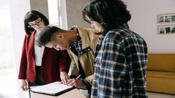 People reviewing and signing real estate documents during an inherited property discussion.