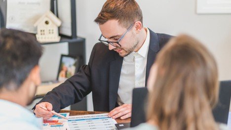Mortgage professional reviewing VA loan cost options with home buyers at a desk.