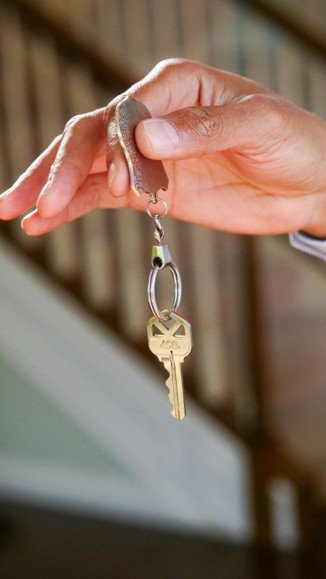 Hand holding house keys representing the tradeoffs between renting and buying a home in Mansfield Texas.