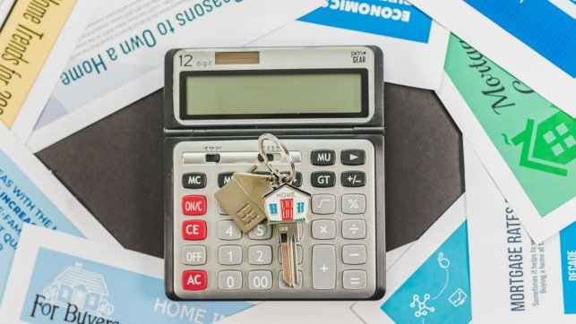 Calculator, house keys, and real estate paperwork used to estimate seller closing costs and net proceeds.