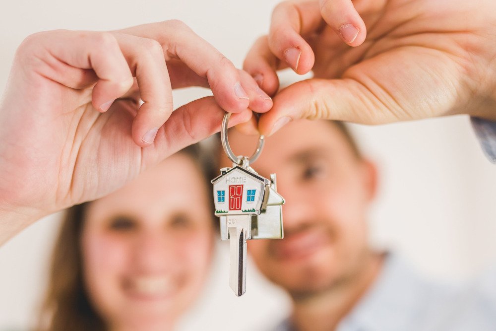Couple holding house keys at a doorway for a blog about buying a home in DFW with low credit.