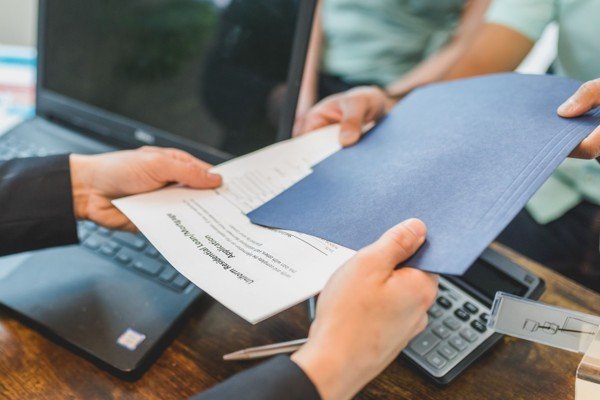 Real estate documents being handed to a buyer during a first-time home buyer program review in Texas.