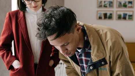 Seller signing updated real estate paperwork with an agent present inside a home.