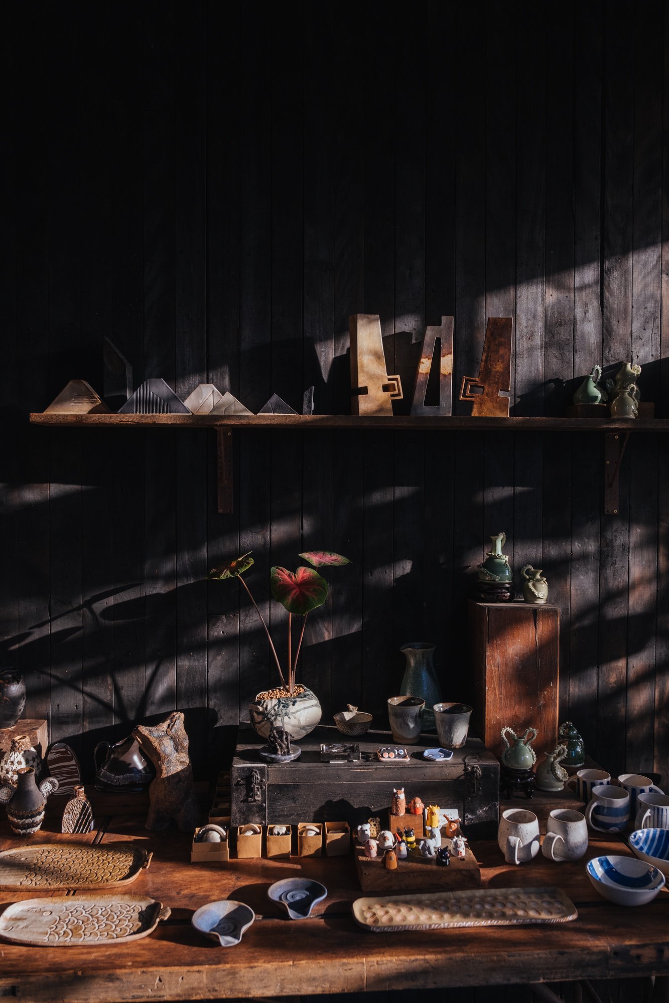 An afternoon photograph of Lab 266 black wall and display table full of handmade ceramic wares.
