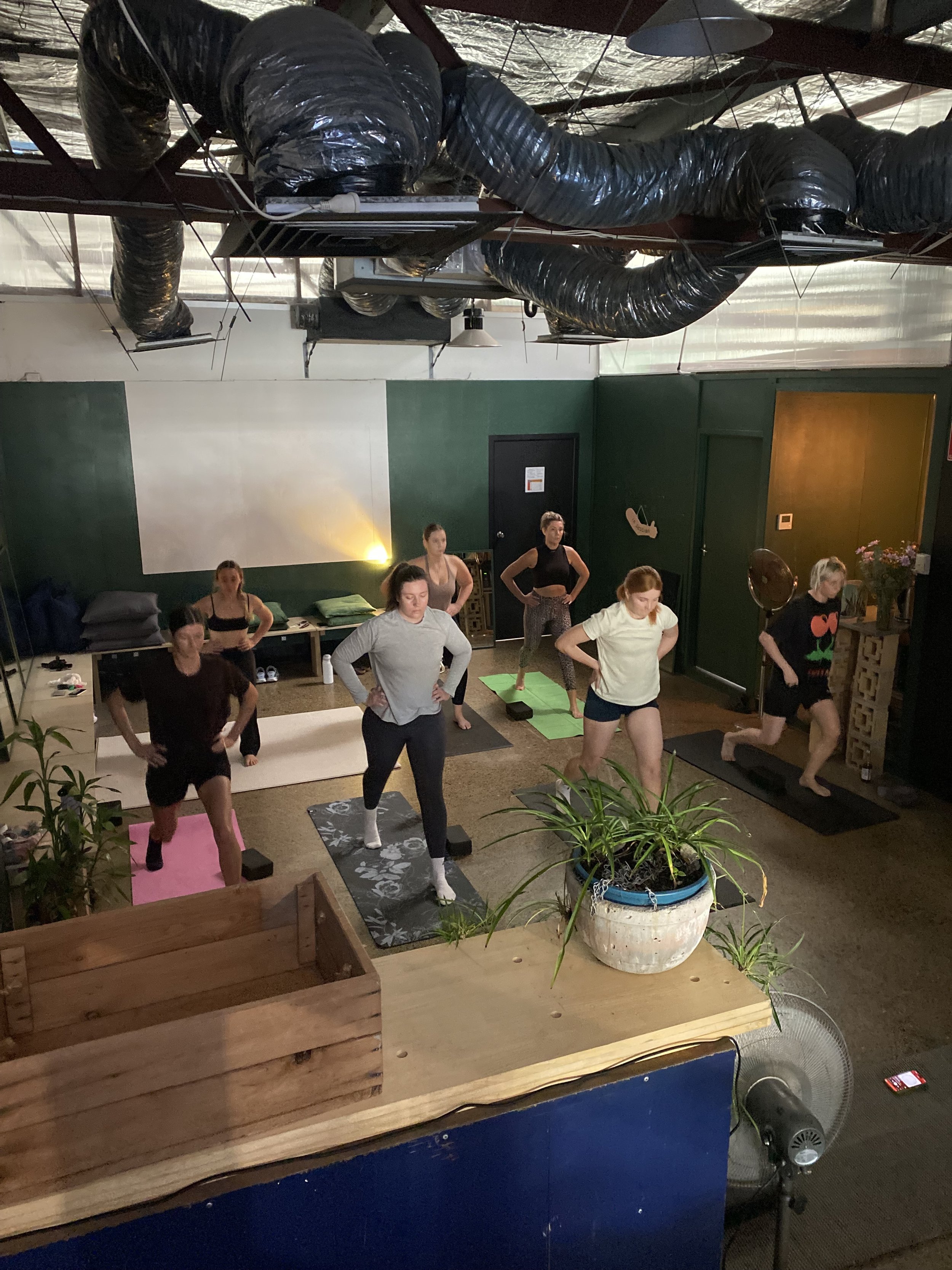 A woman is modelling in front of a white block wall in Vacant Assembly.  There is a photographer and videographer in the foreground building content