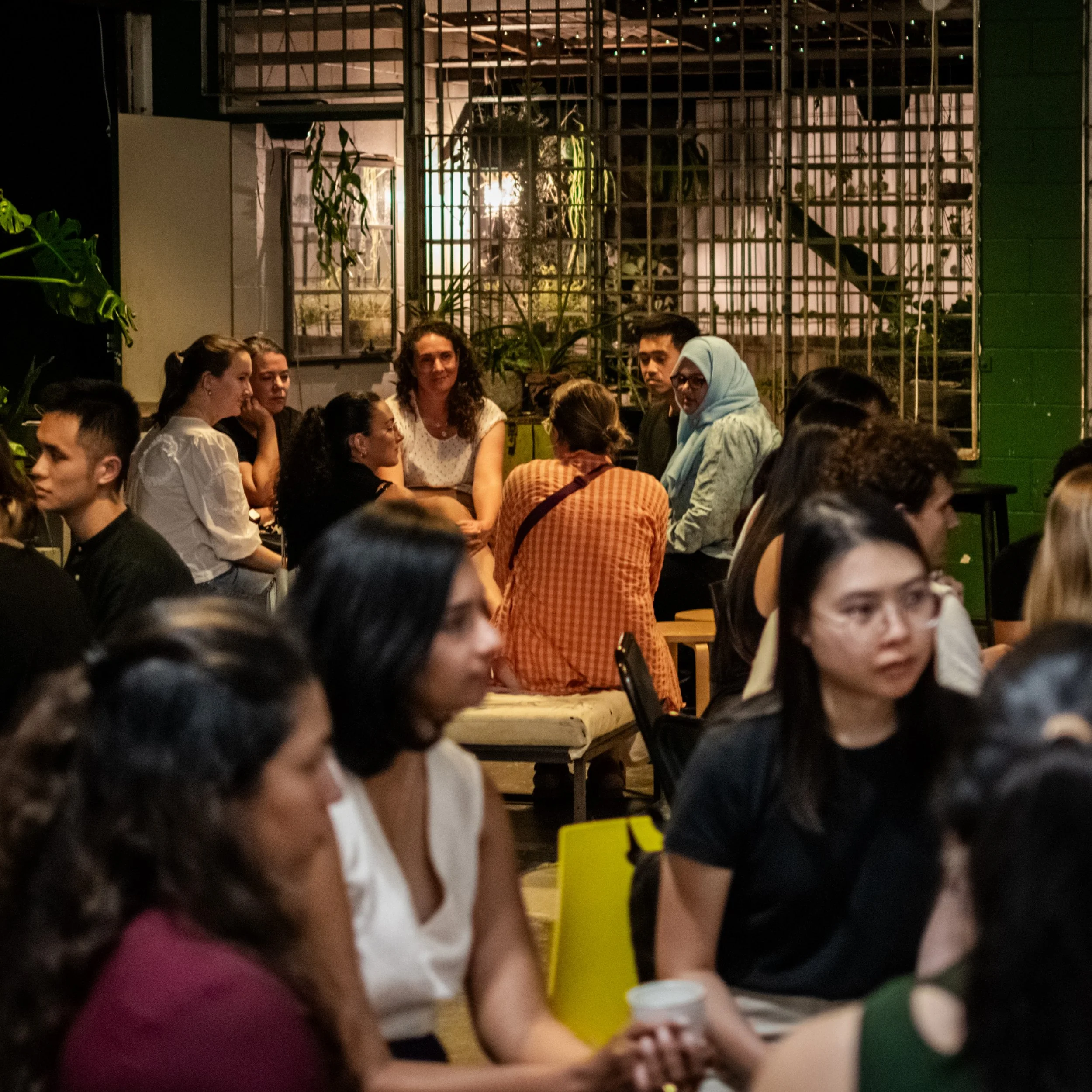 Two groups of people sitting in circles in conversation at an architecture workshop.