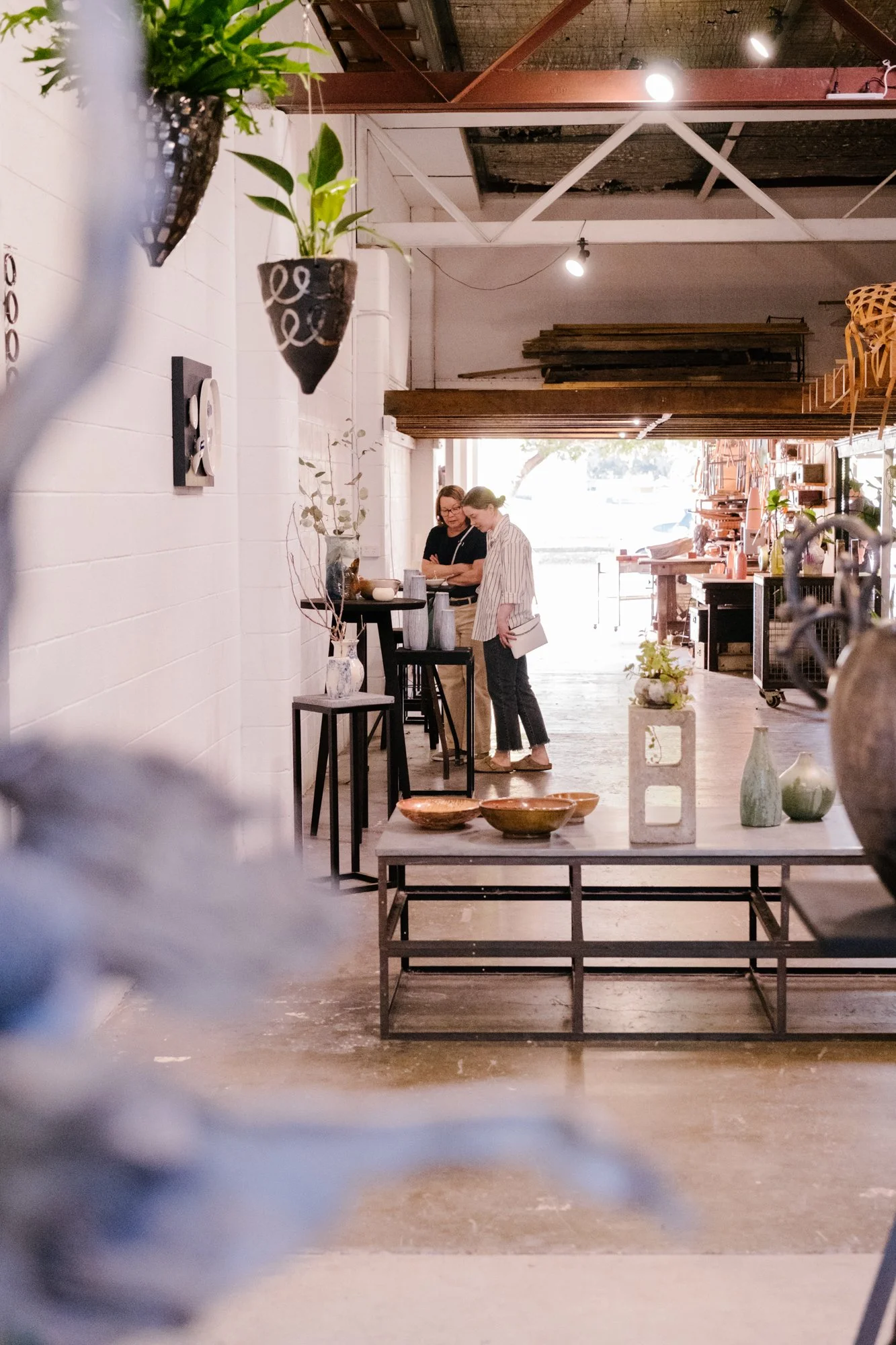Two people at Vacant Assembly looking at a ceramic exhibition.