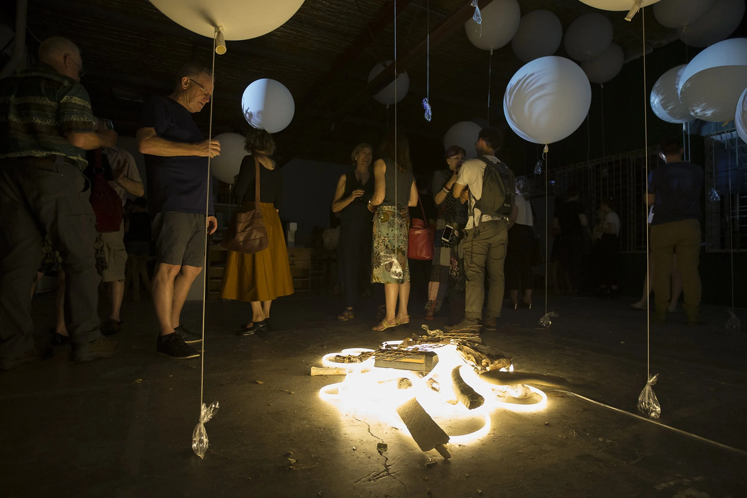 Art Exhibition at Vacant Assembly.  Large art ballons and people around a pile of glowing light rope on the ground.  