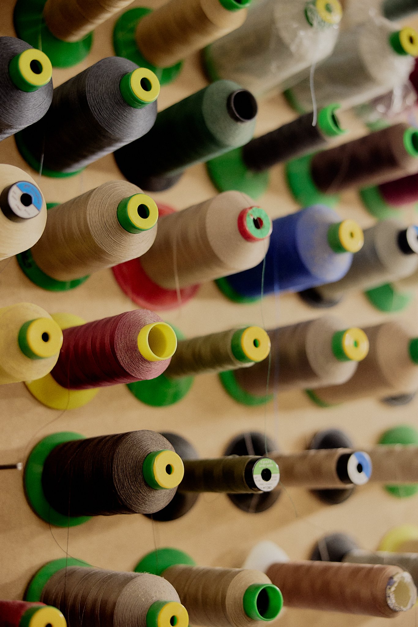 Close-up of colorful sewing thread spools arranged on a wooden surface.