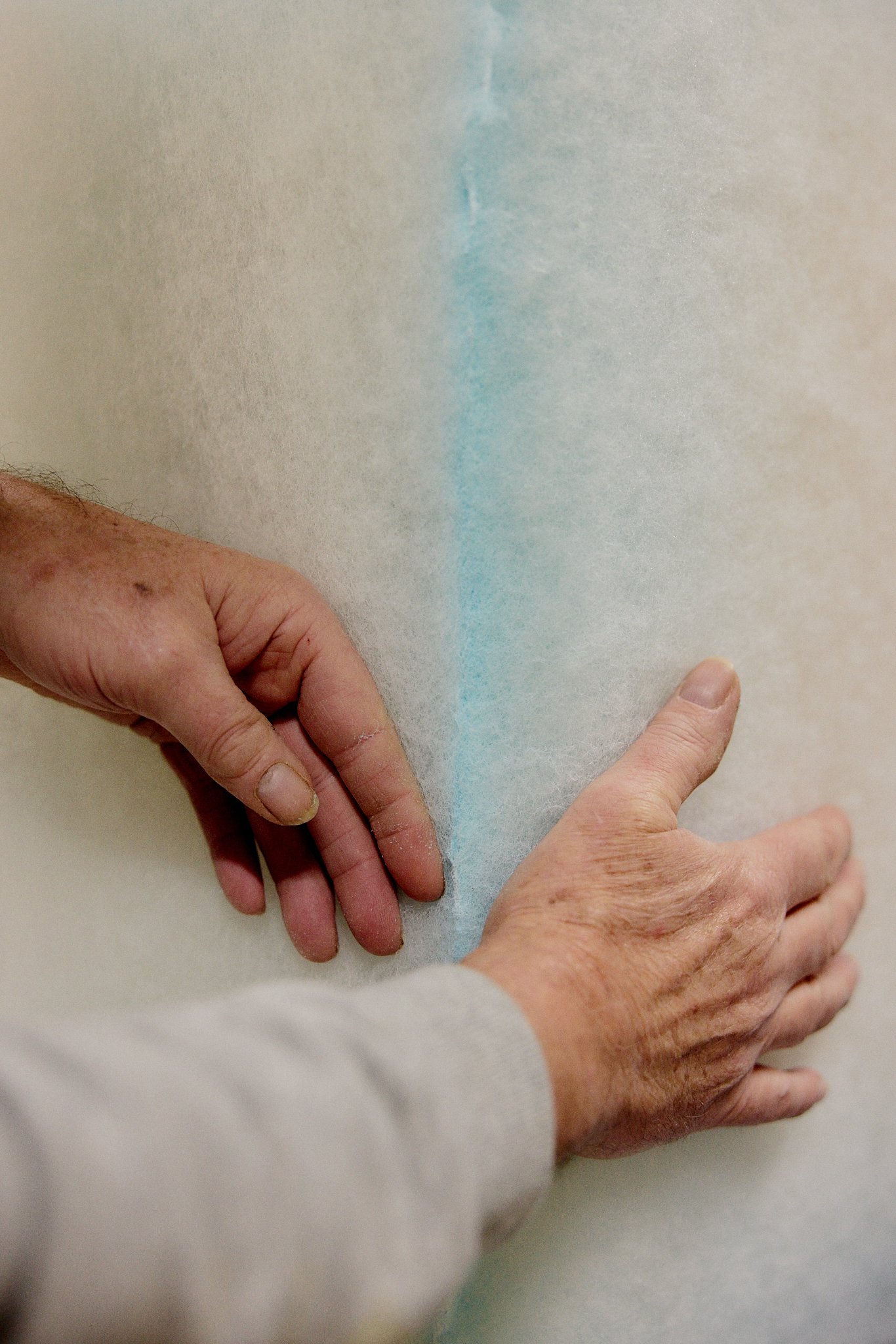 Two hands pulling back a protective plastic cover to reveal a painted wall