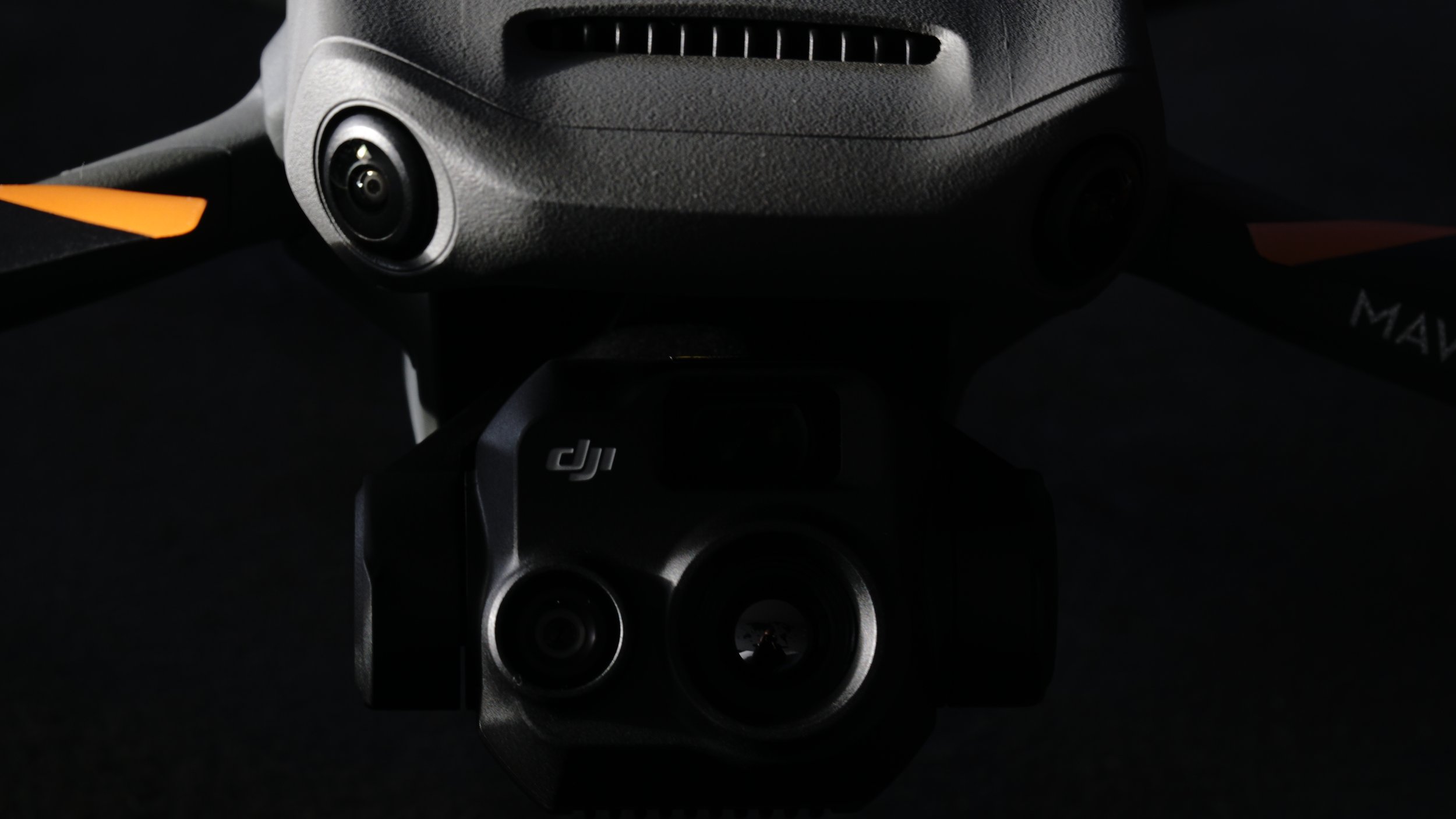 Close-up of a drone with prominently visible camera lenses and DJI logo, set against a dark background.