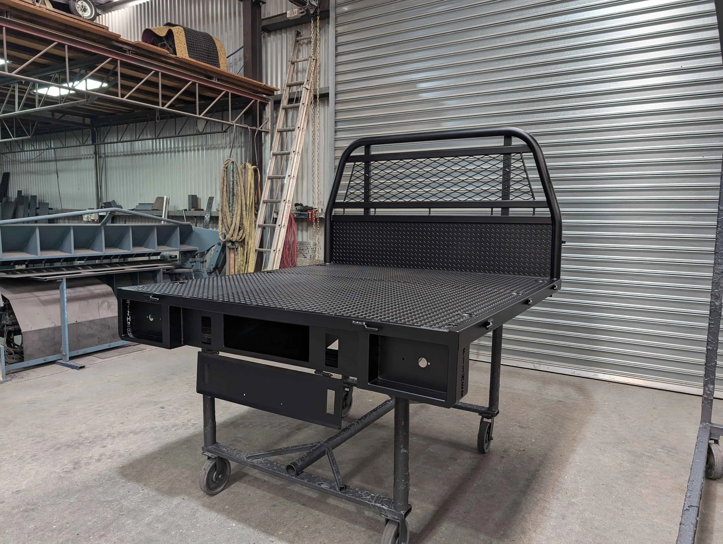 A black metal flatbed with metal mesh and a metal safety rail at the head, custom ute tray and powder coating Wagga Wagga. Sandblasting and powder coating service Wagga with custom truck and ute bodies and ute trays. 