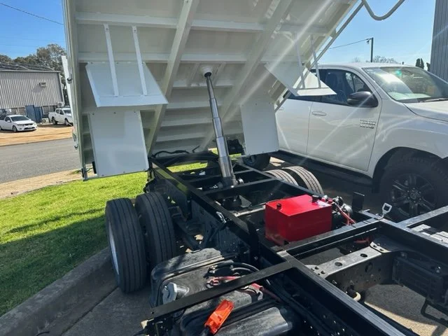 The image shows a tipper truck with its cargo bed lifted, revealing the hydraulic lift mechanism and the vehicle's frame. Custom ute tray and powder coating Wagga Wagga. Sandblasting and powder coating service Wagga with custom ute trays