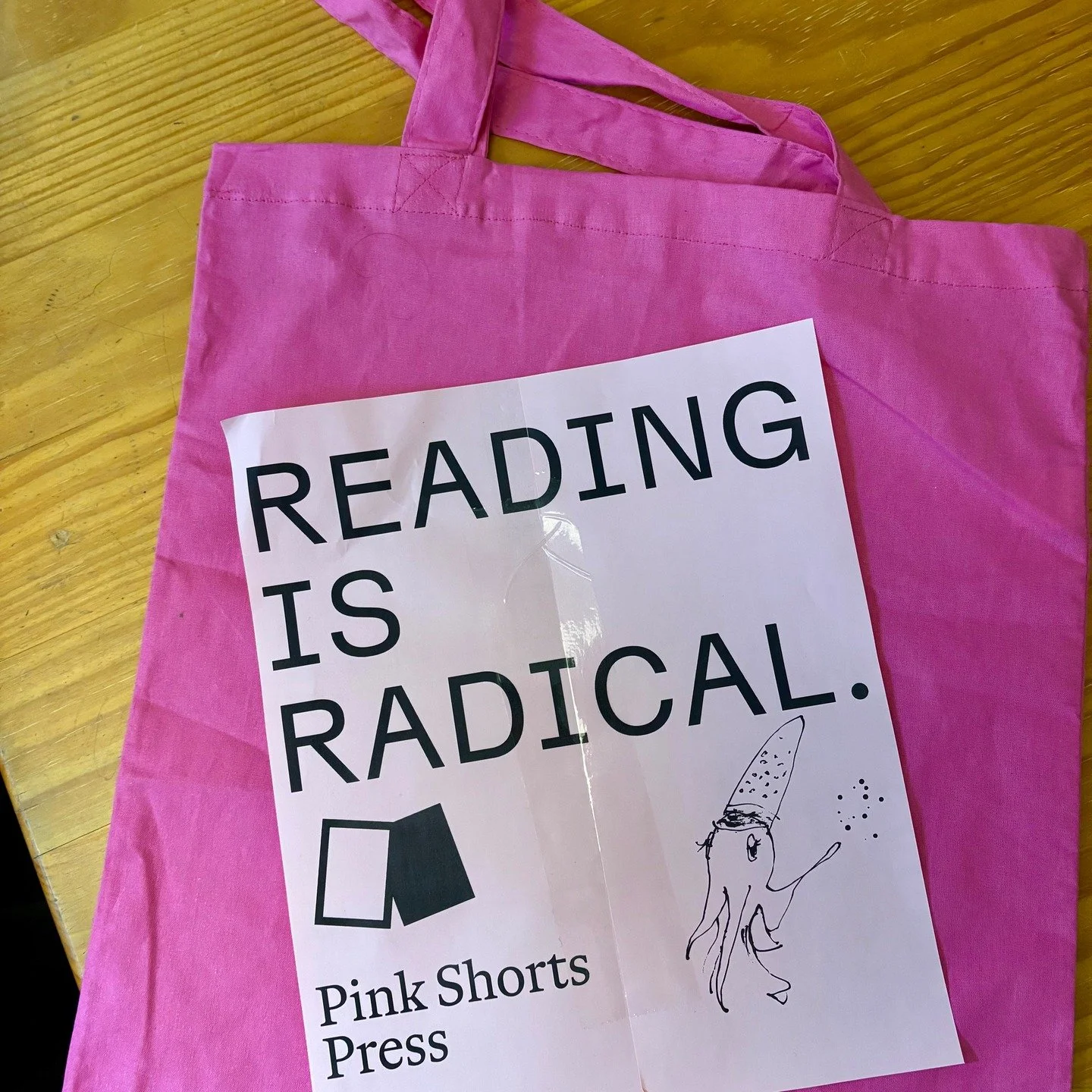 Emily has relented. We are making a tote bag. It is pink. It features a squid called Sia drawn by Rachel of @bitscribbly. From now until Christmas, any orders for our 2025 and March 2026 book subscriptions will come with a tote. It will also be avail