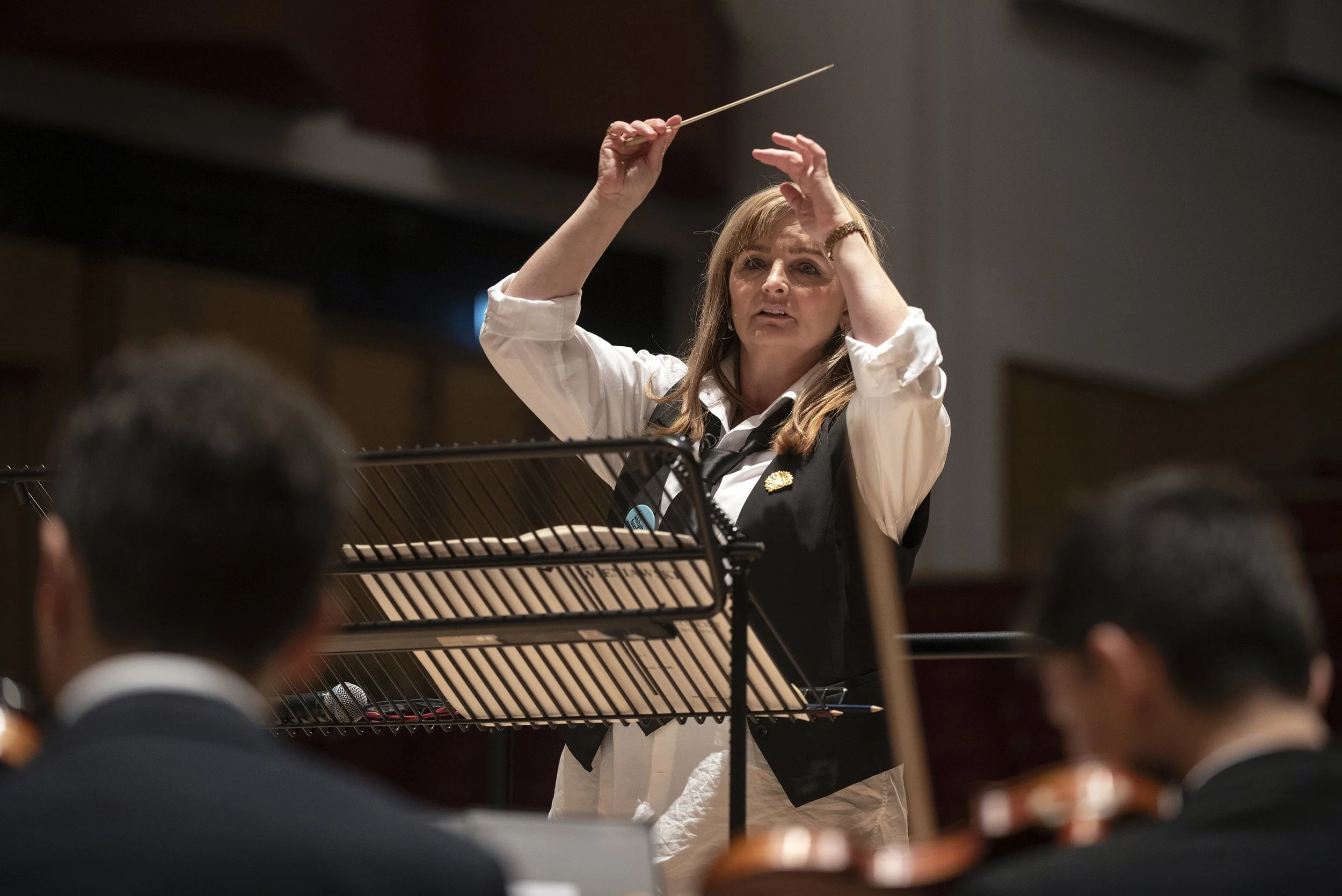Female orchestra conductor leading an orchestra during a performance.