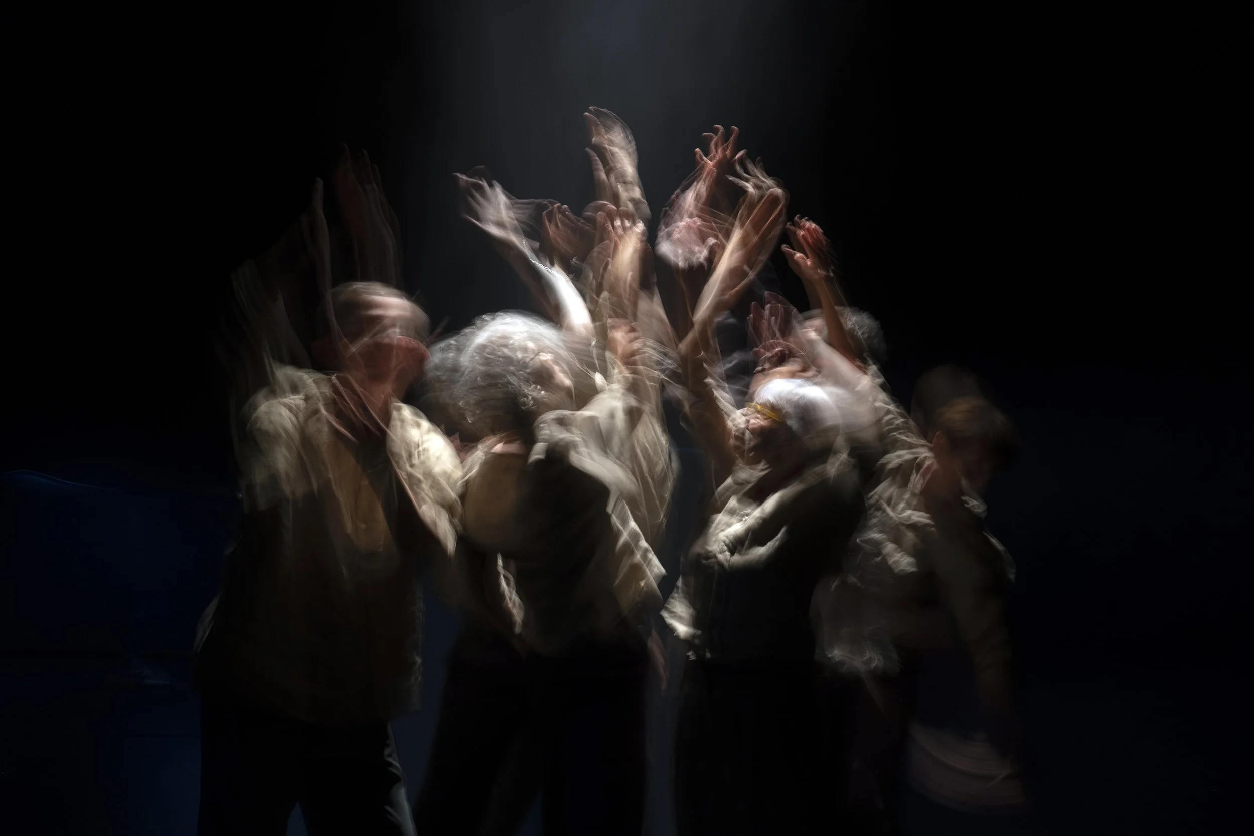 Blurred image of a group of people with raised hands, dancing or celebrating, in a dark setting