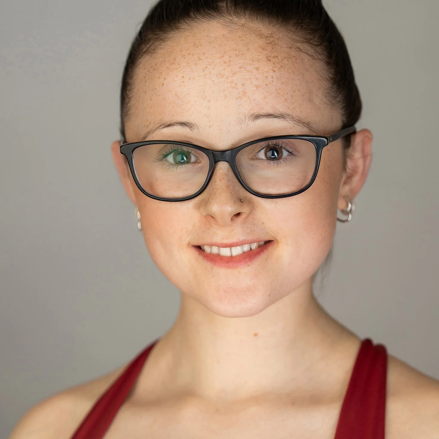 A young woman in red wearing glasses during her headshot portrait session