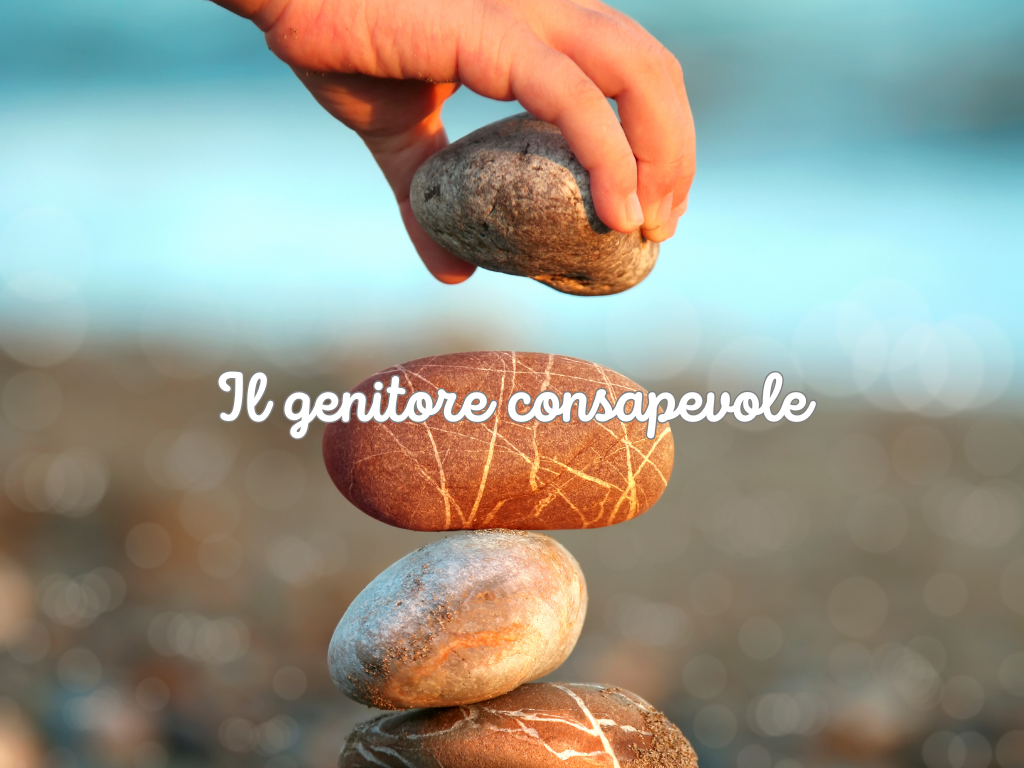 Mano che posiziona un sasso sopra una pila di pietre in equilibrio per il percorso Il Genitore Consapevole