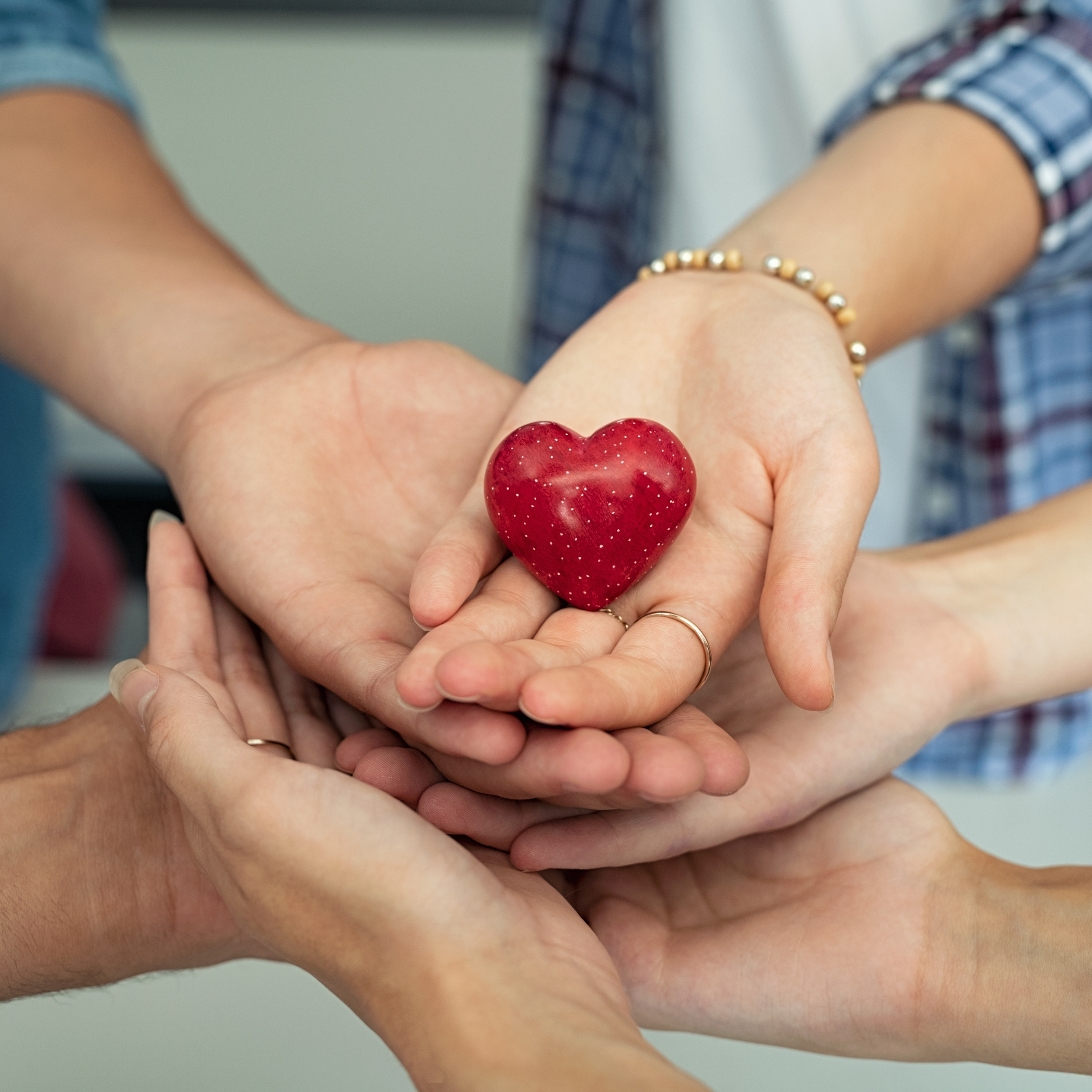 mani sovrapposte che tengono un cuore rosso per il percorso di comunicazione efficace ne La Casa dei Genitori